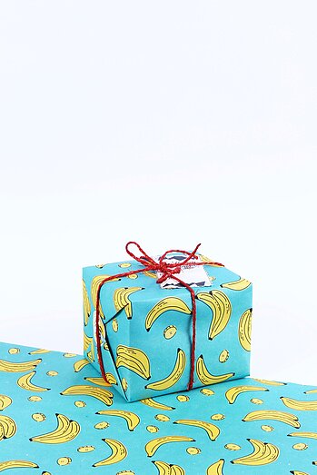 Geschenk verpackt in türkisfarbenem Geschenkpapier mit Banenenmuster