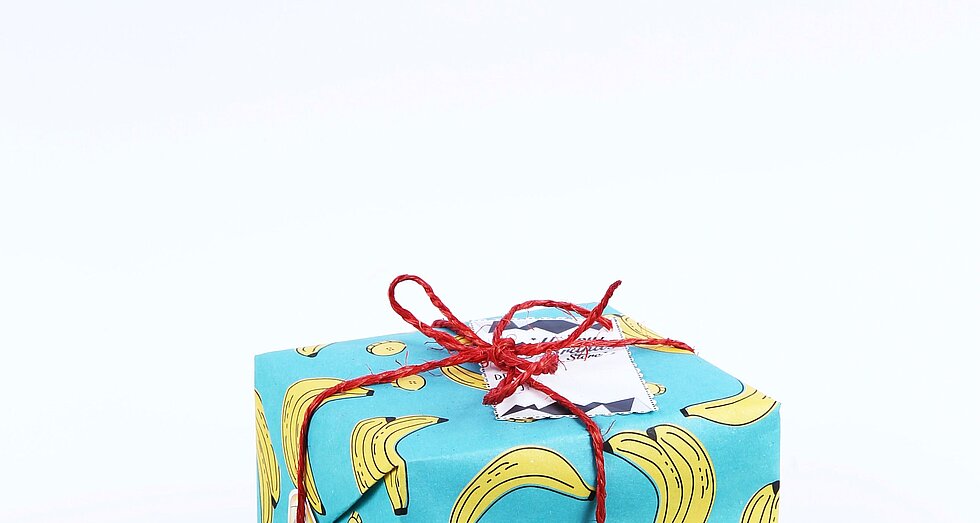 Geschenk verpackt in türkisfarbenem Geschenkpapier mit Banenenmuster