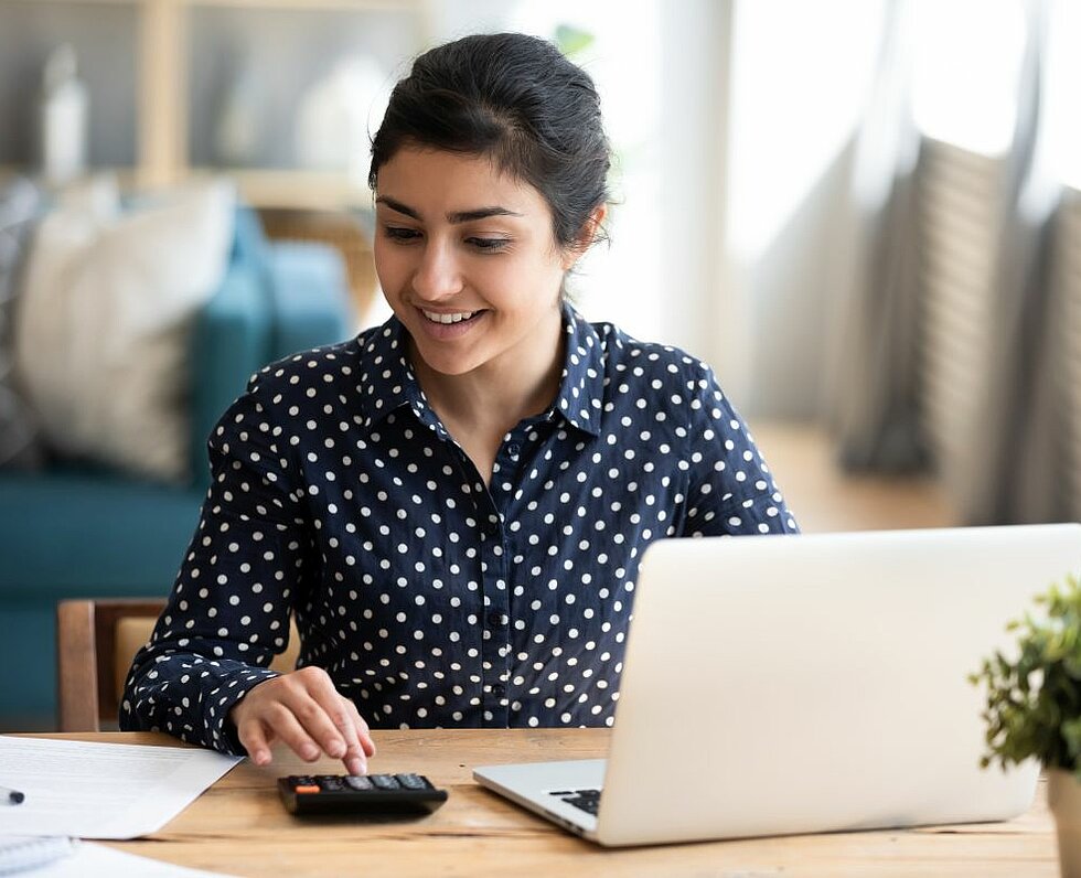 Frau mit Laptop und Taschenrechner