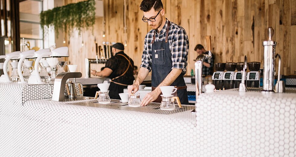 Junger Barista in Café bei der Kaffeezubereitung