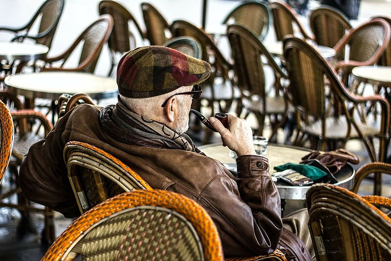 Pfeife rauchender Rentner in Café