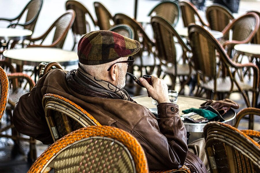 Pfeife rauchender Rentner in Café