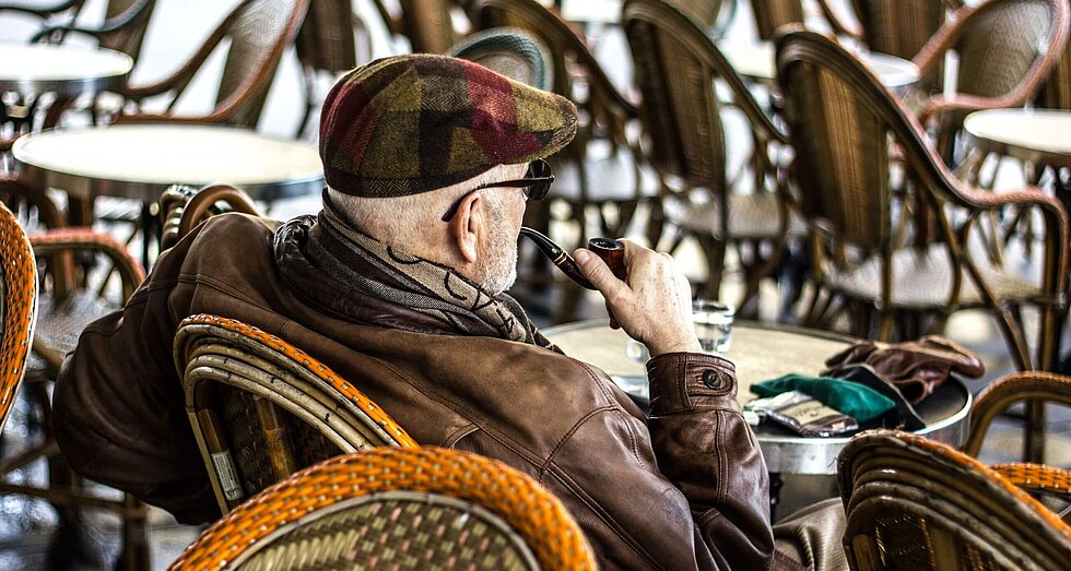 Pfeife rauchender Rentner in Café