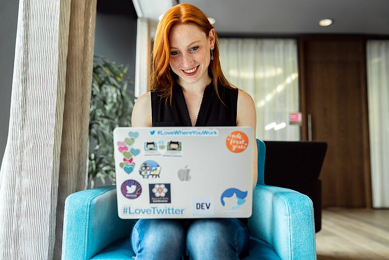 Lächelnde rothaarige Frau am Laptop