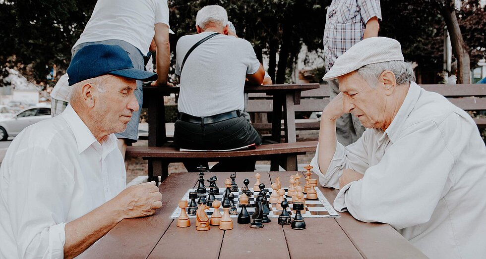 Zwei ältere Männer beim Schachspielen an einem Tisch im Park