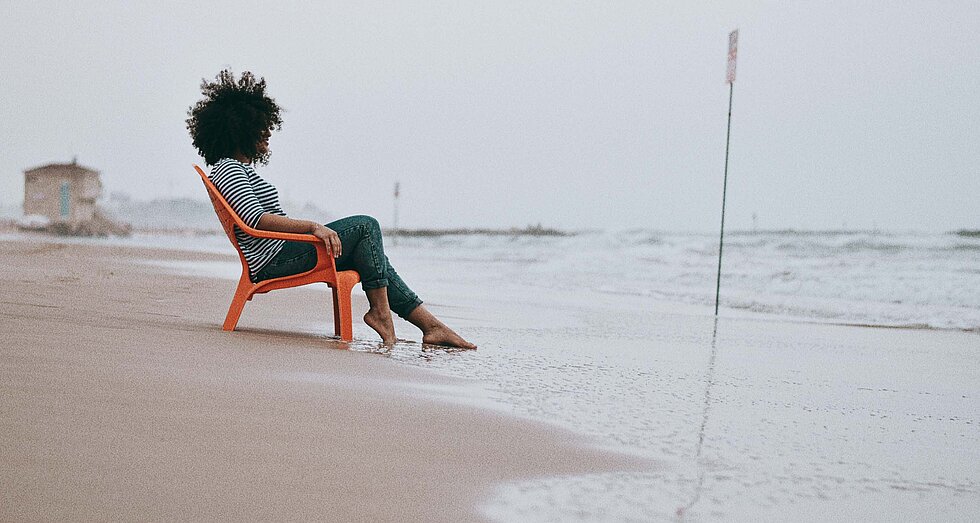 Frau in Liegestuhl an der Nordsee mit Blick aufs Meer