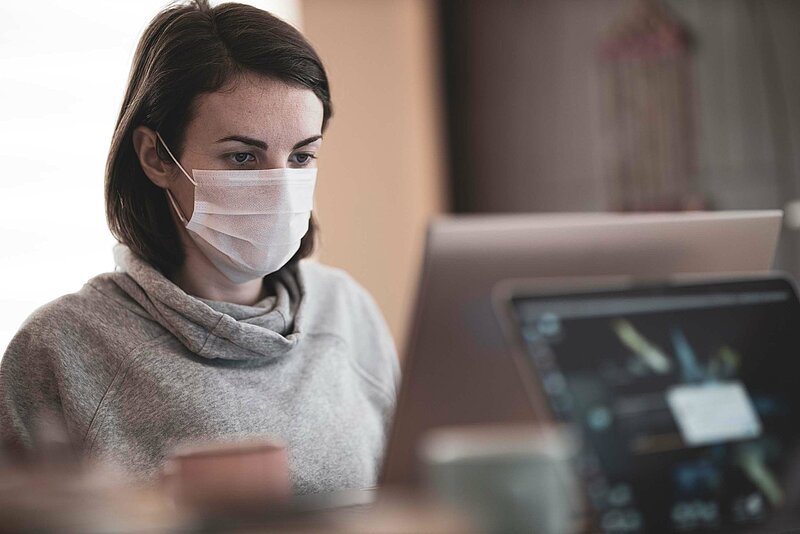 Corona-Steuer-engin-akyurt-unsplash Frau mit Atemmaske vor Laptop