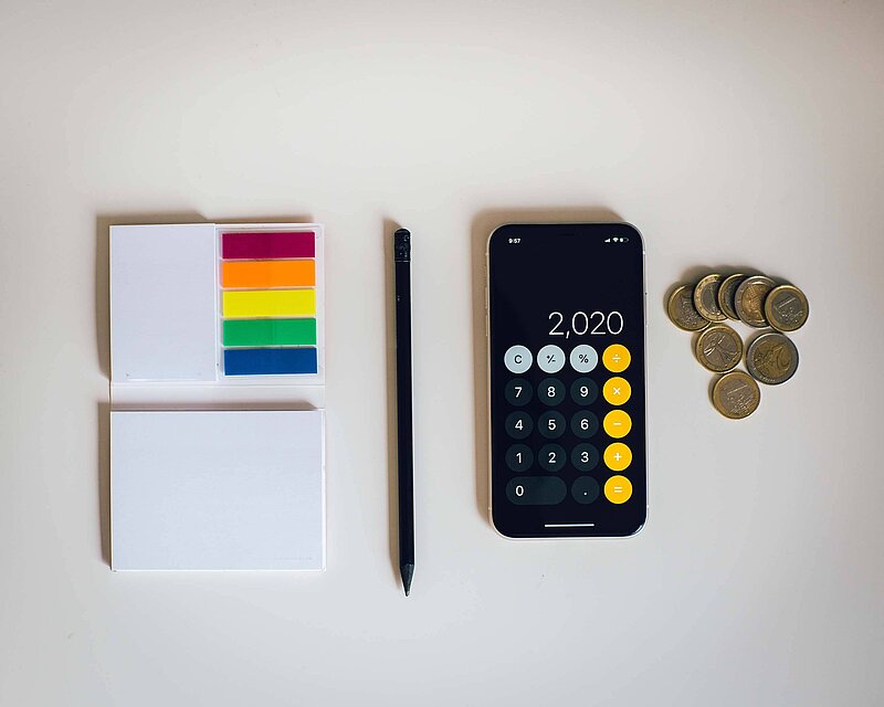 Stuerklassenrechner_amol-tyagi-UZFCQPNc4bs-unsplash Post it's neben Handy und Münzgeld auf weißem Untergrund