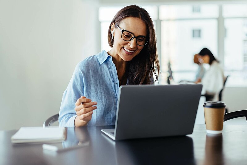 Freundlich lächelnde Business-Frau, die ein Online-Geschäftstreffen in ihrem Büro hat