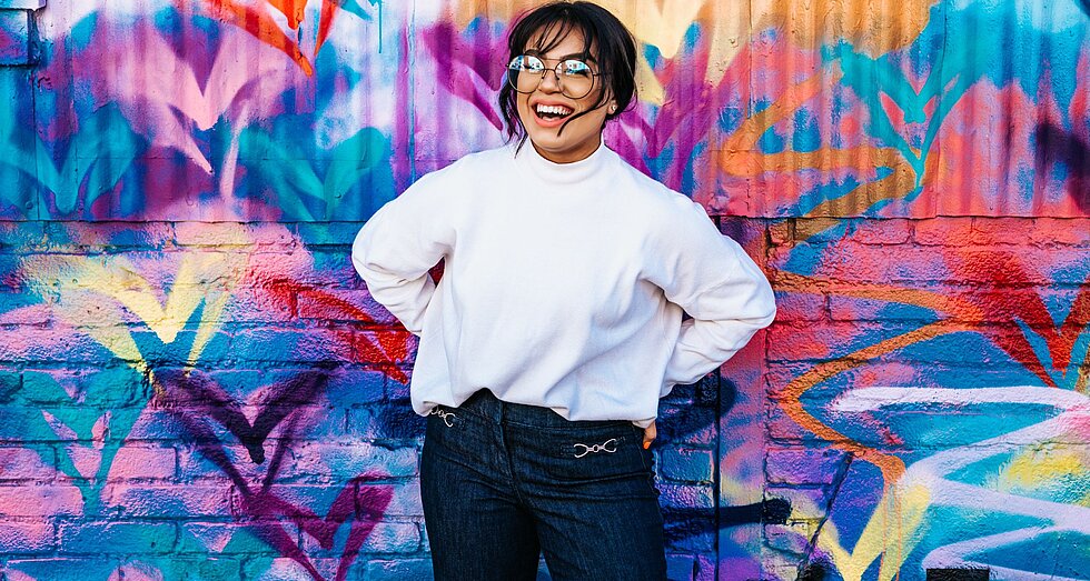 Junge Frau vor bunter Graffitiwand