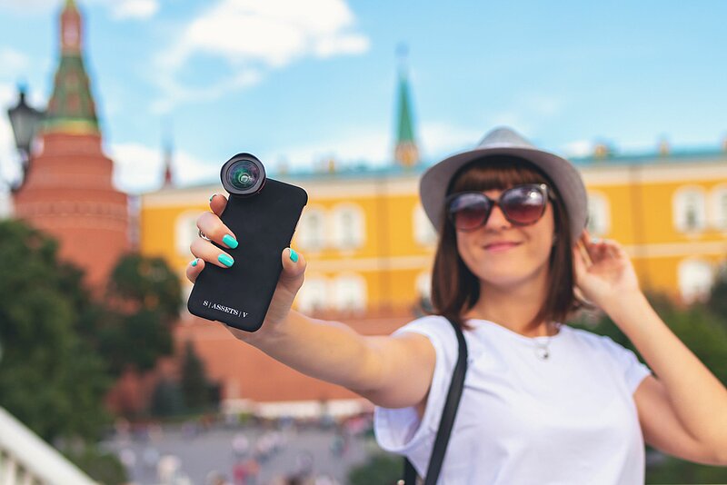Influencer_Steuern-Artem Beliaikin-Unsplash Junge Influencer:in mit Smartphone vor Sehenswürdigkeit