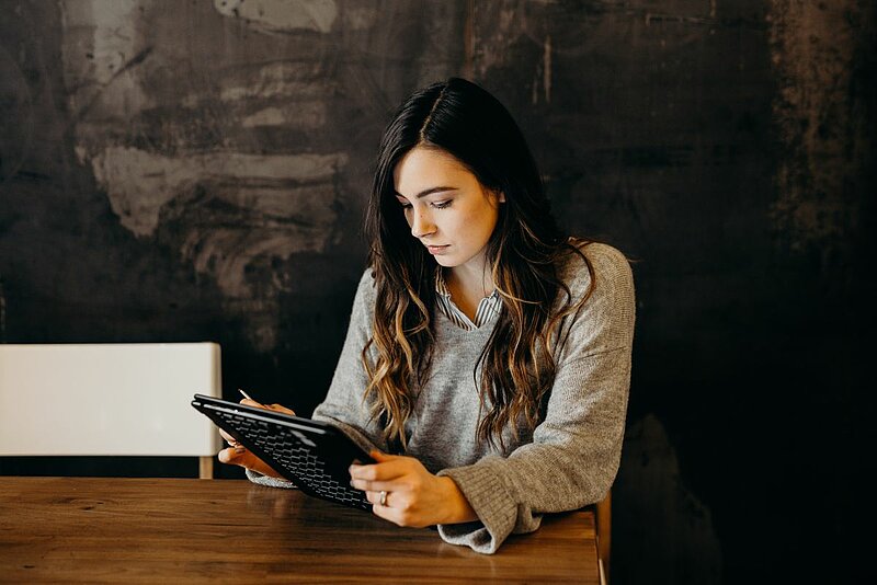 Steuerbescheid prüfen-Brooke Cagle-Unsplash. Frau mit Tablet am Schreibtisch