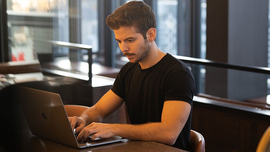 Gewerbesteuererklärung-Anthony Riera-Unsplash Mann in schwarzem T-Short beim Arbeiten am Laptop