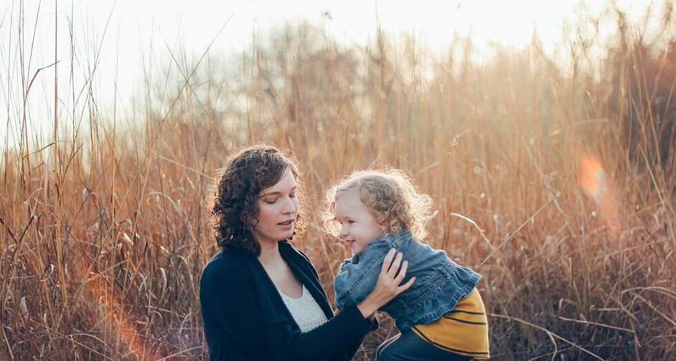 Frau mit Kind in der Natur beim Sonnenuntergang