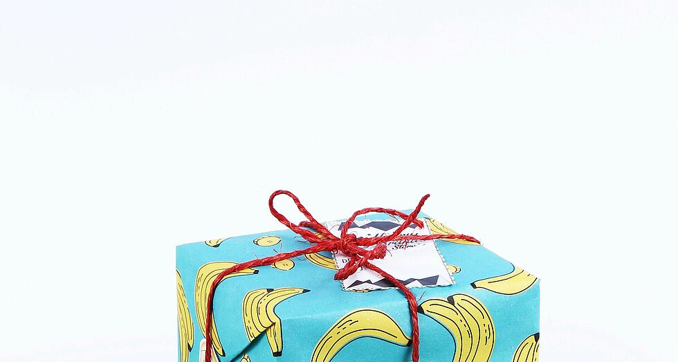 Geschenk verpackt in türkisfarbenem Geschenkpapier mit Banenenmuster