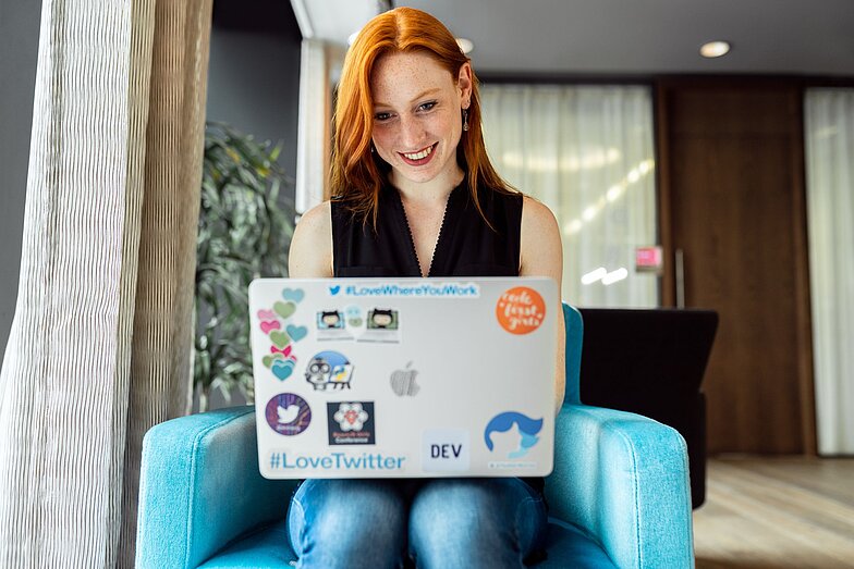 Lächelnde rothaarige Frau am Laptop