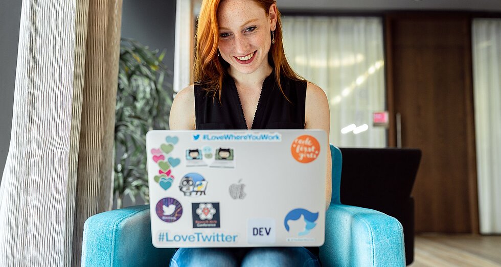 Lächelnde rothaarige Frau am Laptop