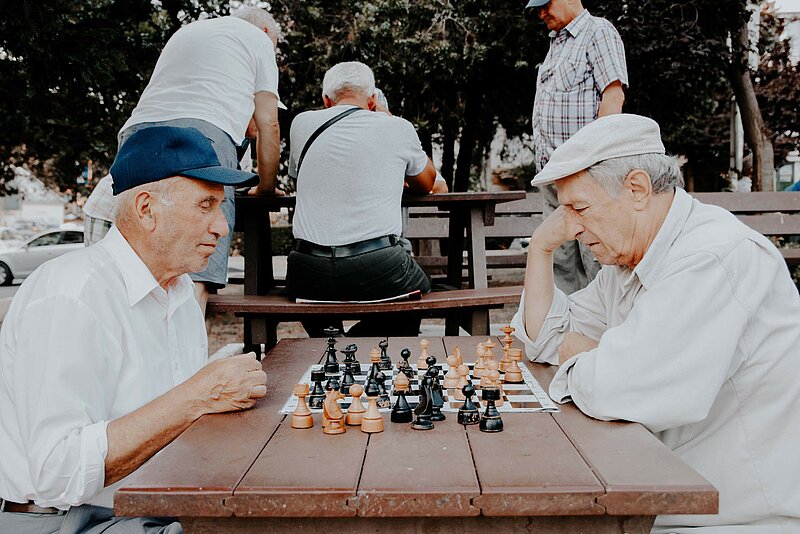 Zwei ältere Männer beim Schachspielen an einem Tisch im Park
