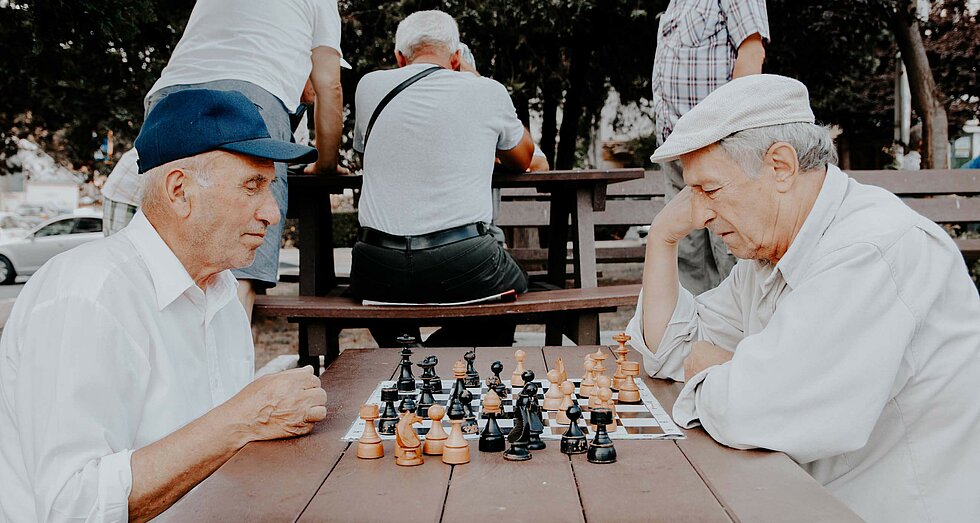Zwei ältere Männer beim Schachspielen an einem Tisch im Park