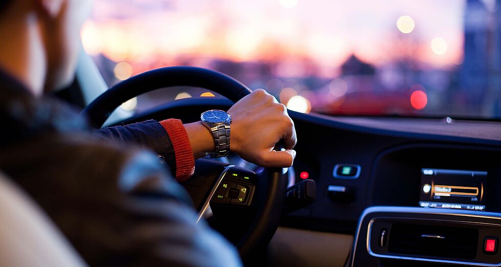 Man von hinten am Lenkrad eines Autos