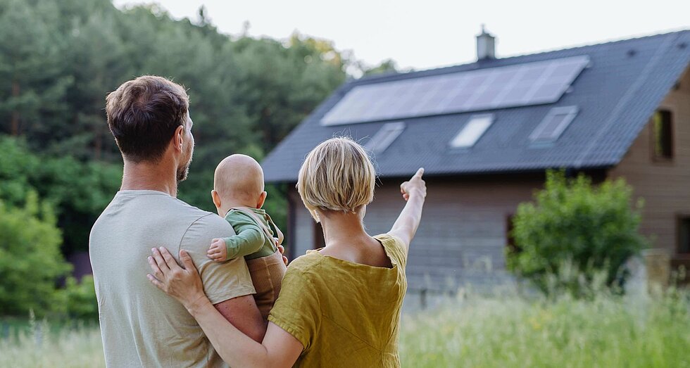 Junge Familie vor ihrem neu erworbenen Grundstück