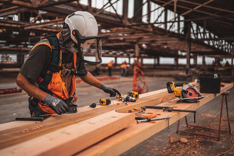 Schreiner mit Schutzhelm bei der Arbeit mit Holz