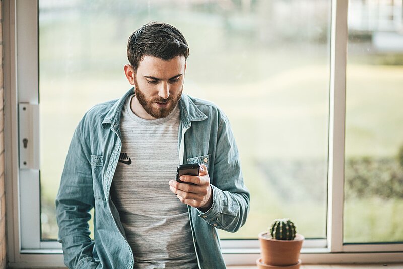 Arbeitnehmerpauschbetrag Junger Angestellter prüft seine Lohnabrechnung auf seinem Smartphone