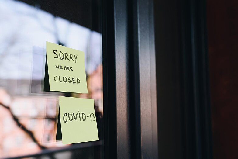 Zwei Post it's mit Informationen zur Schließung an einer Glasfront.