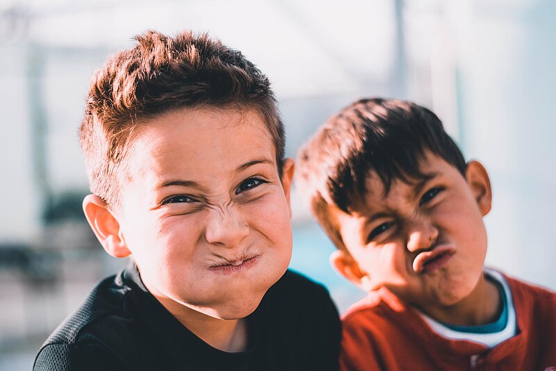 Kinderbetreuungskosten-Austin Pacheco-Unsplash Zwei Jungs, die Grimmassen ziehen