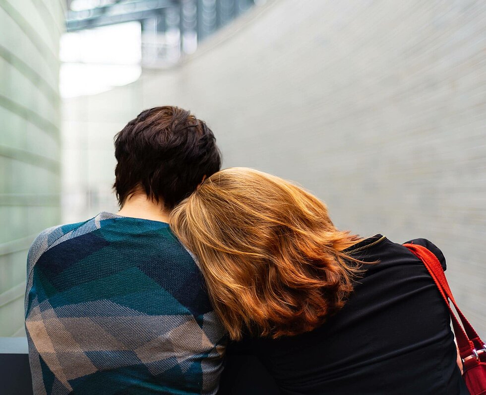 Junge Frau lehnt ihren Kopf auf die Schulter ihres Partners