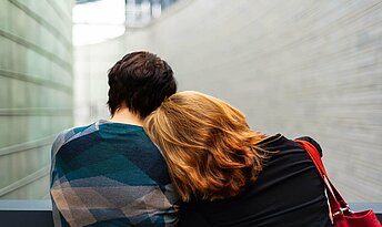 Junge Frau lehnt ihren Kopf auf die Schulter ihres Partners