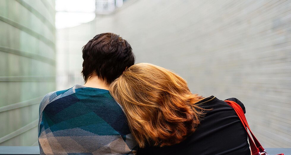 Junge Frau lehnt ihren Kopf auf die Schulter ihres Partners